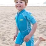 Enfant en maillot de bain bleu sur la plage au coucher du soleil.