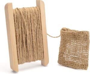 Cotton rope on wooden spool with burlap bag for decoration or craft projects.