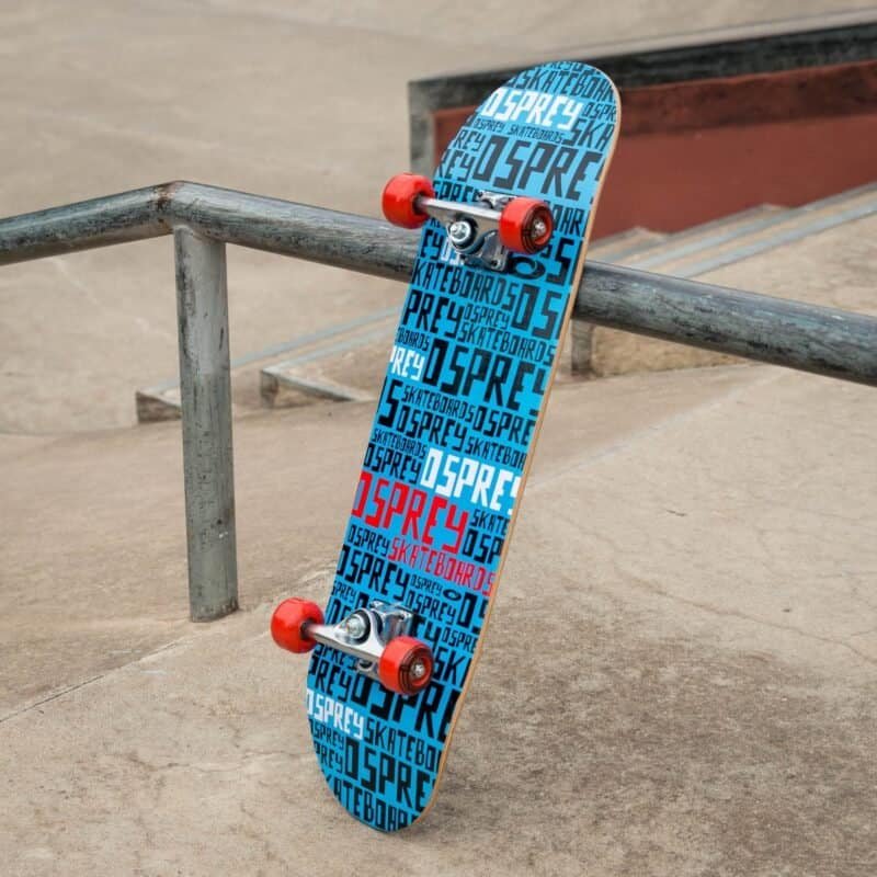 Skateboard met blauwe en rode branding op betonnen skateboardbaan.