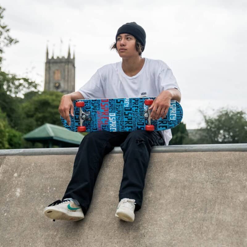 Skateboarder met skateboard ontspannen op een skateramp buiten in de stad.