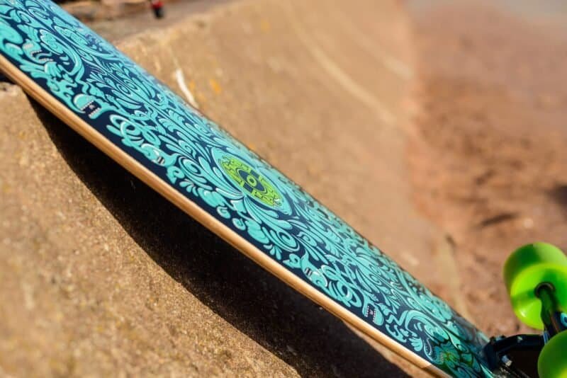 Cheerful skateboard with blue print and green details on sand base.