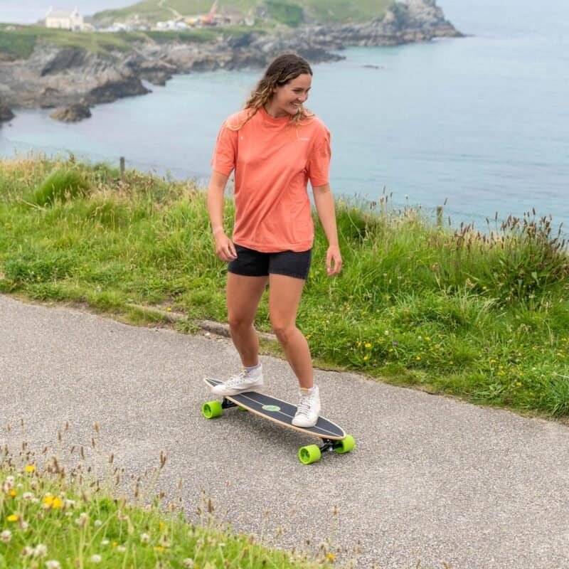 Skateboarding by the sea with female skater in outdoor sportswear.