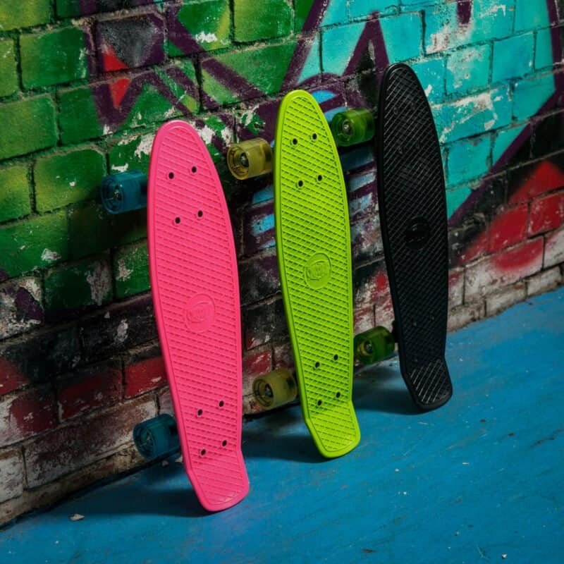 Bunte Skateboards und Helme hängen an einer mit Graffiti bemalten Wand in einem Skatepark.