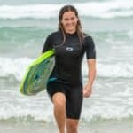 Planche de surf aux motifs colorés sur la plage en combinaison de plongée.