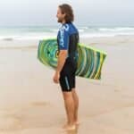 - Planche de surf colorée avec des rayures bleues, vertes et jaunes.