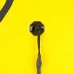 Oeil en plastique avec corde noire pour planches de surf et combinaisons de plongée sur fond jaune.