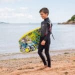 Planche de surf colorée et combinaison de plongée pour les enfants à la plage.