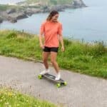 Skateboarding au bord de la mer avec une patineuse en tenue de sport de plein air.