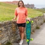 Skateboard et femme à l'extérieur, skateboarder avec longboard sur la promenade de la plage, photo de style de vie à l'extérieur, équipement de skate à la mode, parc de skate et mer en arrière-plan.
