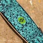 Craie pour skateboard avec des illustrations bleues et vertes et des détails colorés sur fond noir.