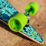 Skateboard coloré avec des roues vertes vibrantes et un motif graphique sur le plateau. Parfait pour les sports de plein air et le skateboard.