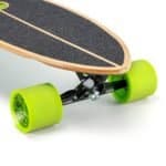 Petite image d'un skateboard longboard avec des roues vertes et une plate-forme en bois. Convient pour une utilisation en extérieur et pour la pratique du skateboard.