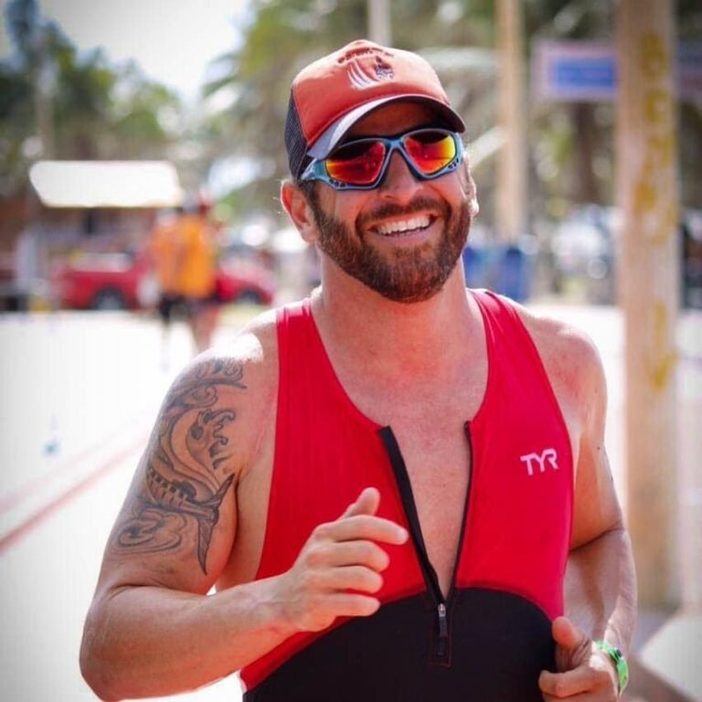 Man running in a red triathlon suit wearing Glogglz sunglasses.