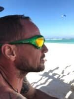 Man wearing green Glogglz sunglasses enjoys a sunny day at the beach.