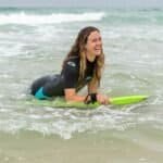 Zonnige vrouw surft op zee met surfplank, genietend van buitenplezier.