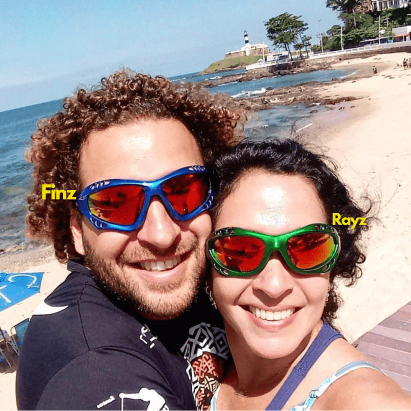 Koppels met sportieve en kleurrijke skibrillen op het strand, genieten van de zon en de zee.
