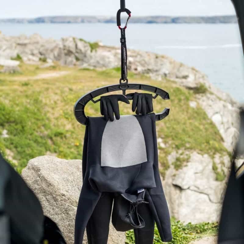 Stand avec équipement de skateboard et gants sur un rivage, idéal pour les sports de plein air et l'aventure.