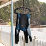 Windsurf wetsuit hanging on a rack outdoors with a scenic mountain background.