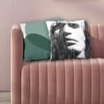Kussen met abstract zwart-wit vrouwenportret en groen grafisch ontwerp op roze bank.