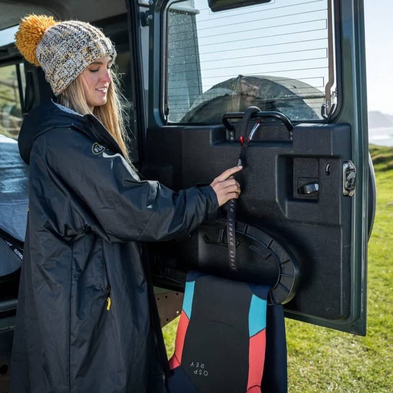 Un patineur charge un skateboard dans un véhicule à l'aide d'une corde. Un snowboard est disponible en plein air pour les jeunes et les moins jeunes.