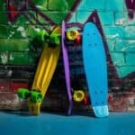 Colourful skateboards and a mini skateboard against a graffiti wall.