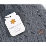 Kleiner goldfarbener Ring mit floralem Muster auf grauem, strukturiertem Hintergrund.