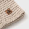 Leren label op beige wollen knitted muts voor buitengebruik.