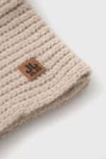 Leren label op beige wollen knitted muts voor buitengebruik.