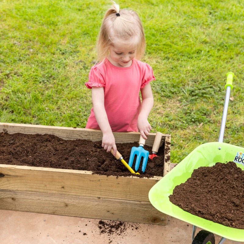 Enfant plantant dans un jardin verdoyant avec des outils de jardinage et un livre pour enfants.