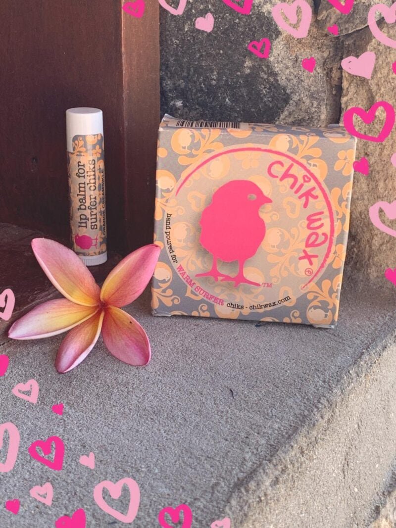 Snufbalsem voor surfers en een Chikk Wax pakket op een stenen muur.