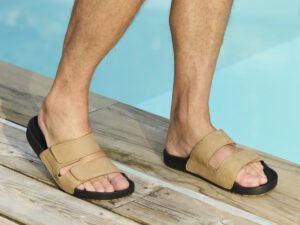 Man zit ontspannen aan de rand van het zwembad met tan Cool Shoe Corp Chill herensandalen aan